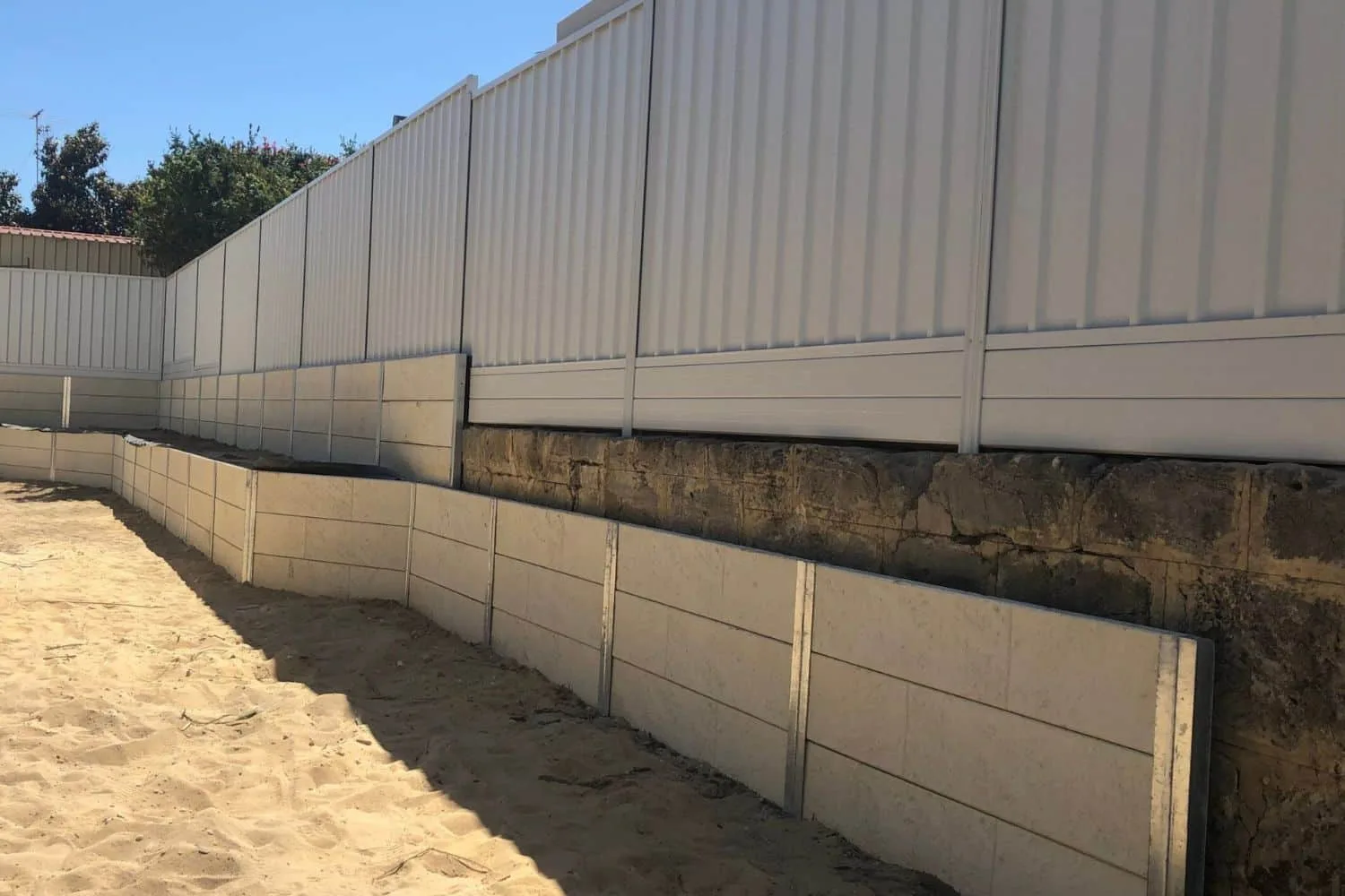 Concrete sleeper retaining wall under a modern fence