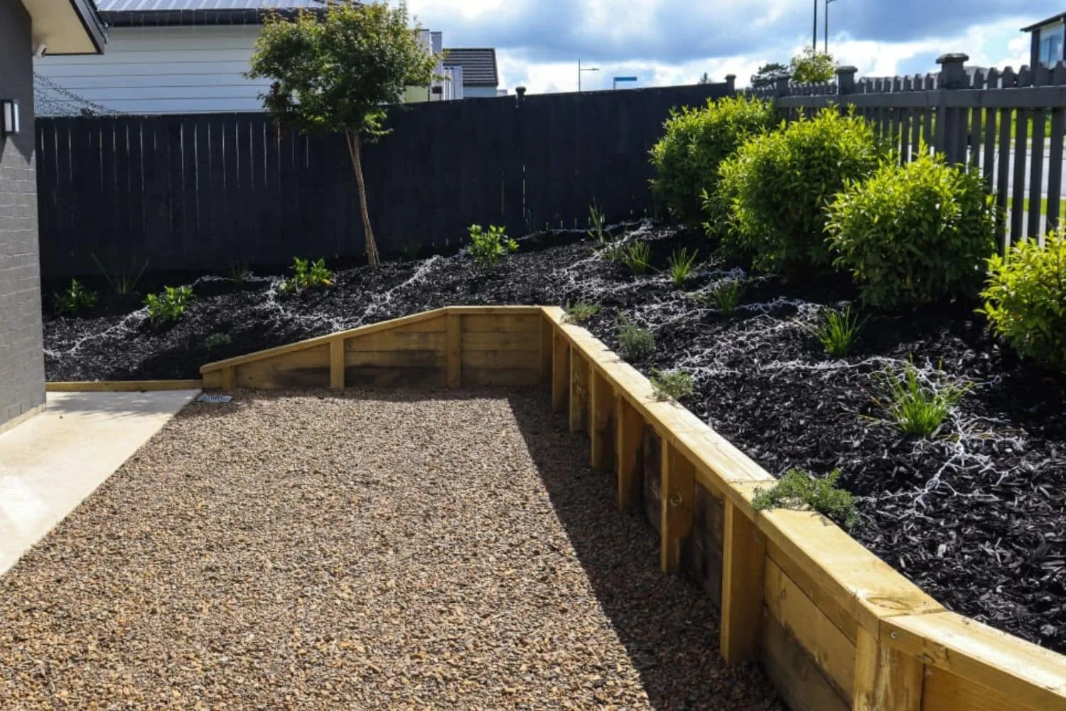 Curved timber retaining wall with flower bed